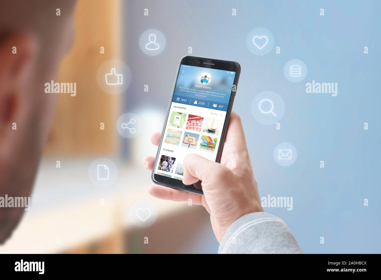 L uomo condivide foto e video con gli amici sui social network concetto. Telefono circondato con concetto icone. Close-up. Foto Stock