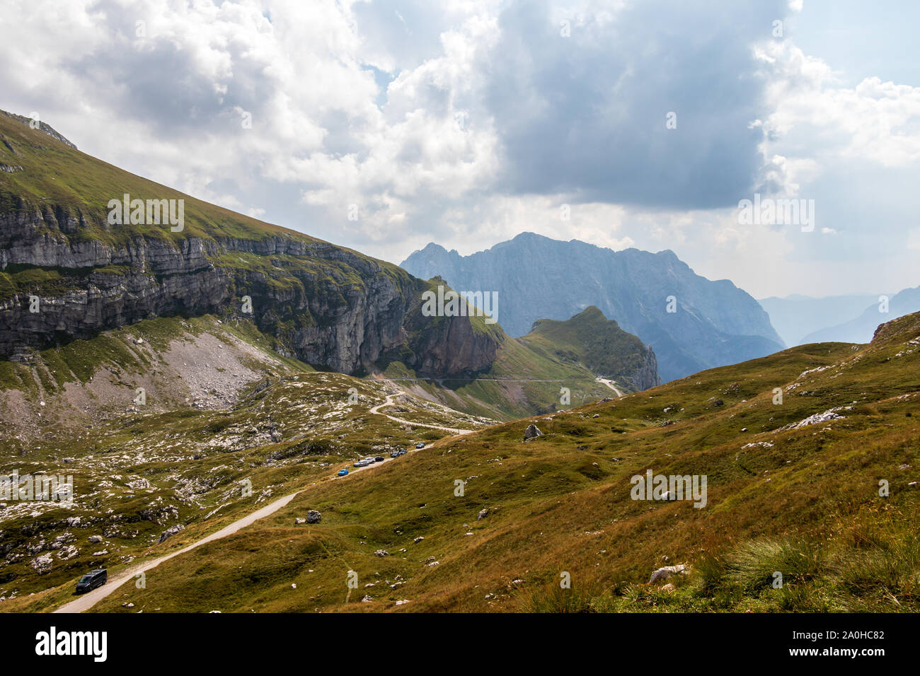 Vista panoramica sul Mangart Road, Mangartska cesta, con parcheggio auto e catena montuosa. Guardare dal Mangart sella, Mangartsko sedlo. Bovec, Slovenia. Foto Stock