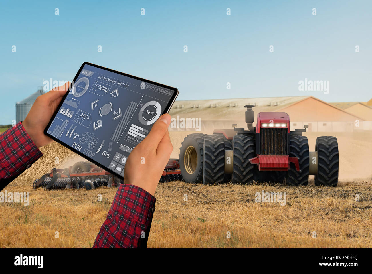 Un agricoltore con tavoletta digitale controlla un autonomo del trattore su una smart farm Foto Stock