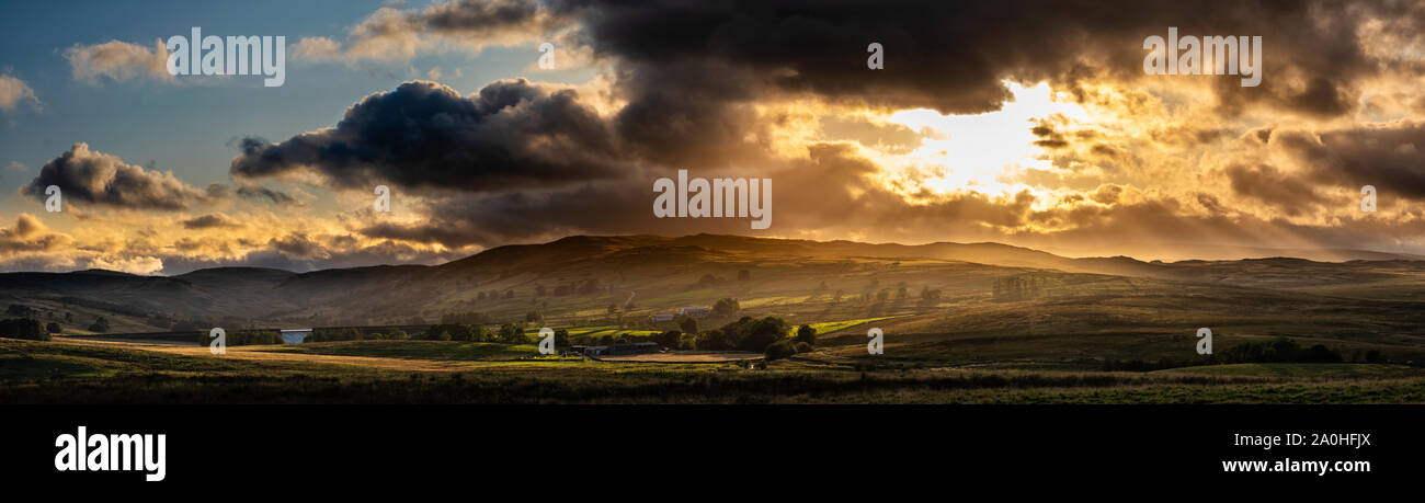 A tarda sera sun taglia attraverso le nuvole sopra il Shap Fells in Cumbria. Foto Stock