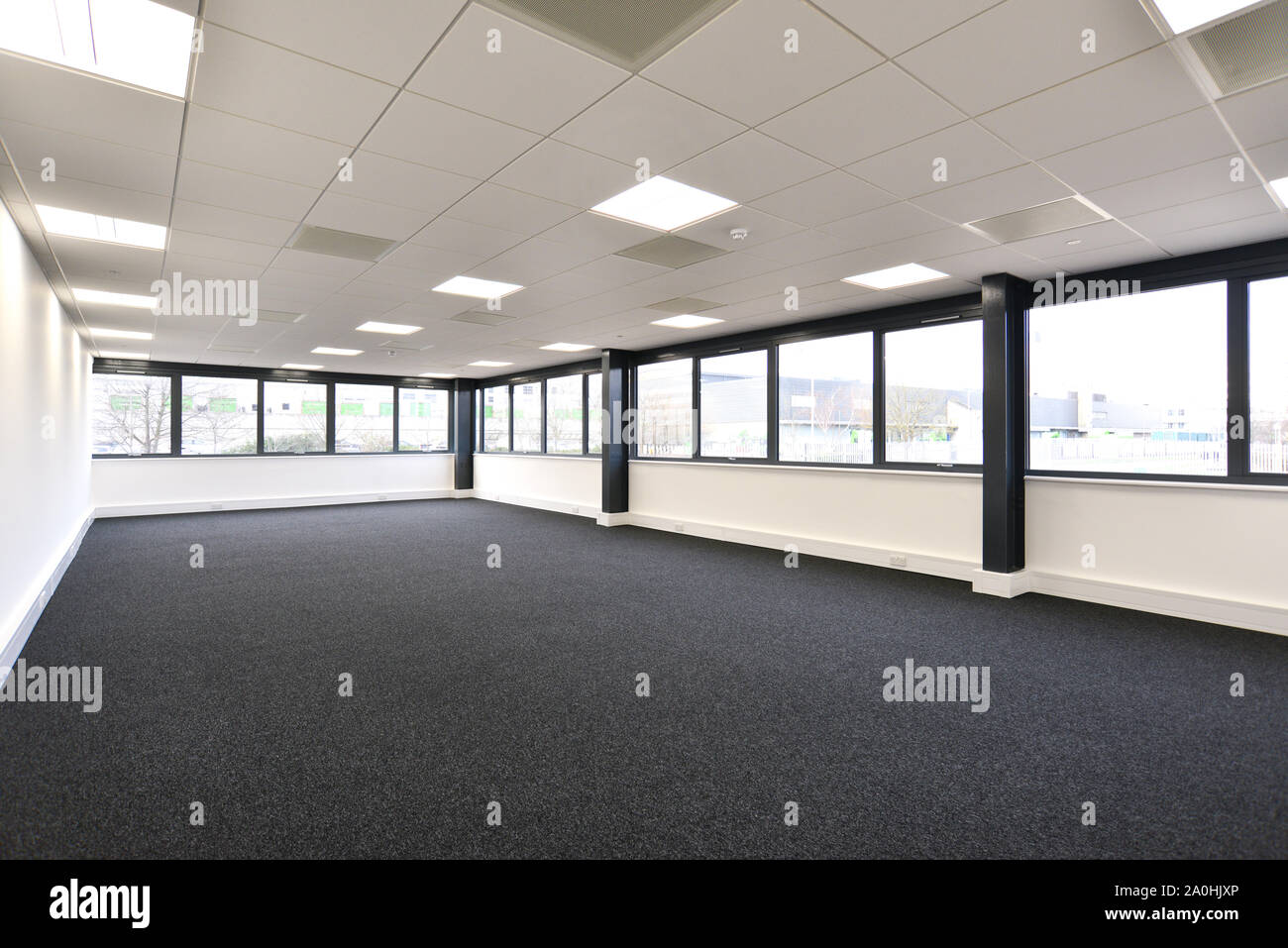 Vista di un nuovo ufficio vuoto area con finestre su due lati e con moquette Foto Stock