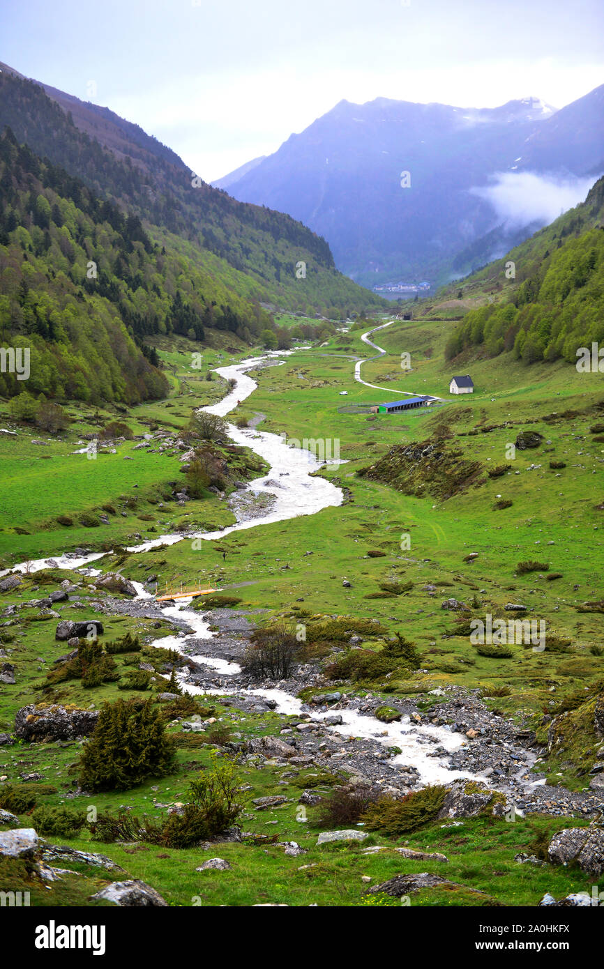 Paesaggio dei Pirenei della corrente di avvolgimento in una valle, prati e casa Foto Stock
