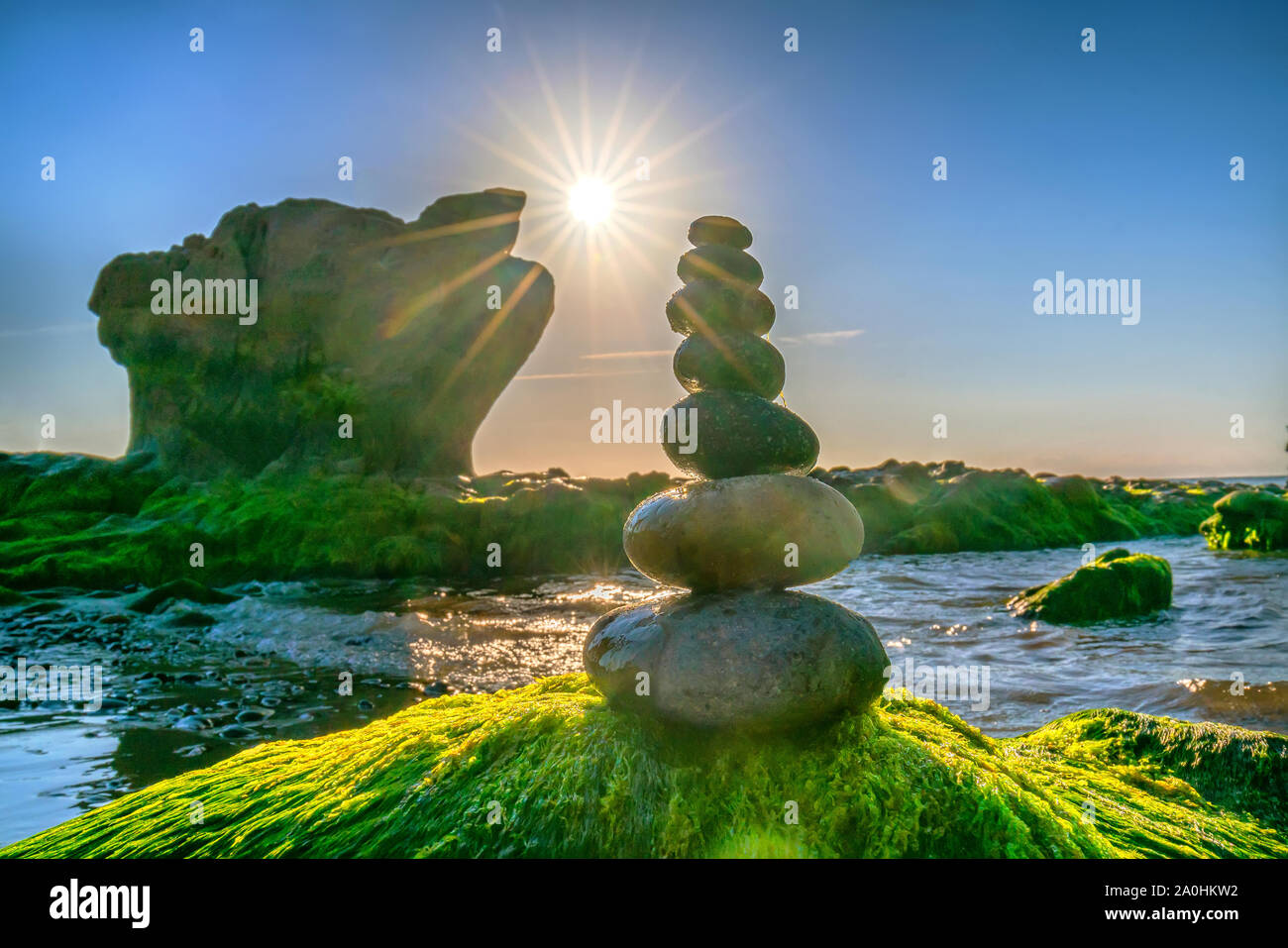 Ciottoli accatastati arte sulle rocce di muschio accoglie favorevolmente Bella nuovo giorno Foto Stock
