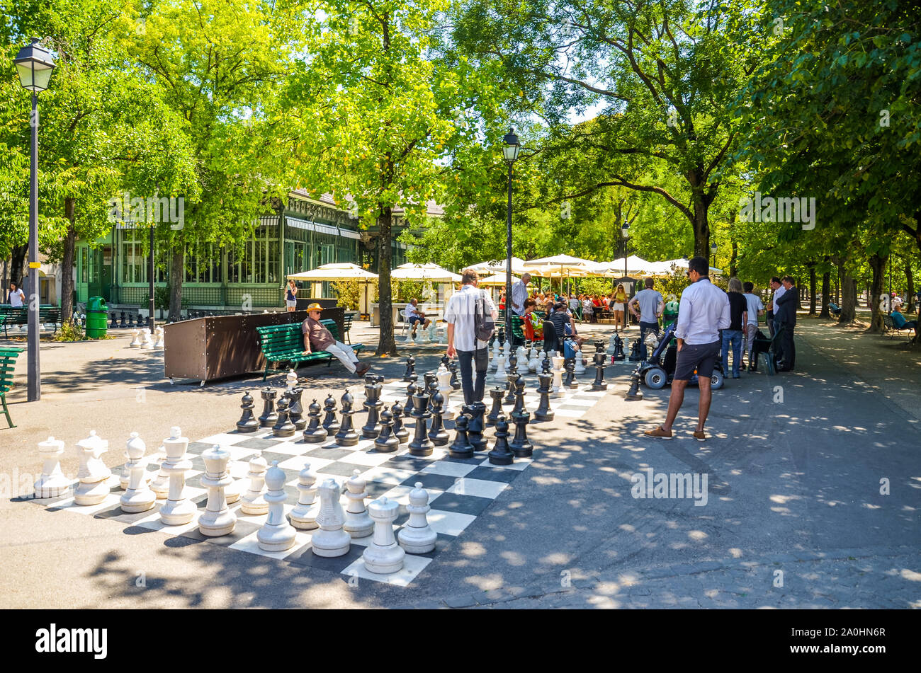 Ginevra, Svizzera - Luglio 19, 2019: persone giocare un esterno di partita a scacchi con gli scacchi giganti di pezzi nel Parc Des Bastions. Scacchi grandi pannelli sono situati all'ingresso del parco nel centro della citta'. Foto Stock