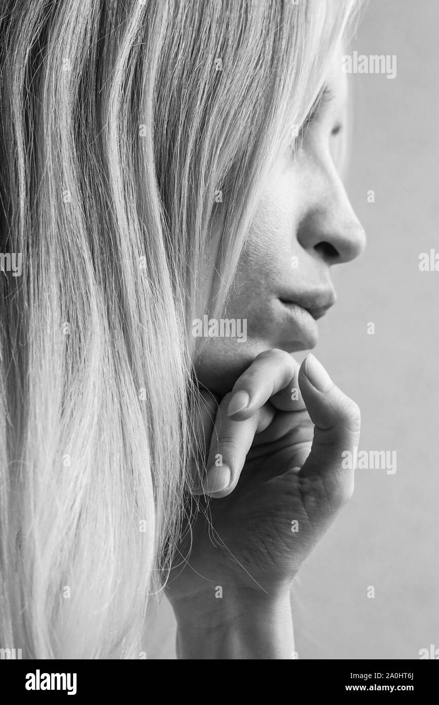 Ritratto morbido di una ragazza giovane con la mano sotto il suo mento, vista laterale nel profilo, foto in bianco e nero Foto Stock