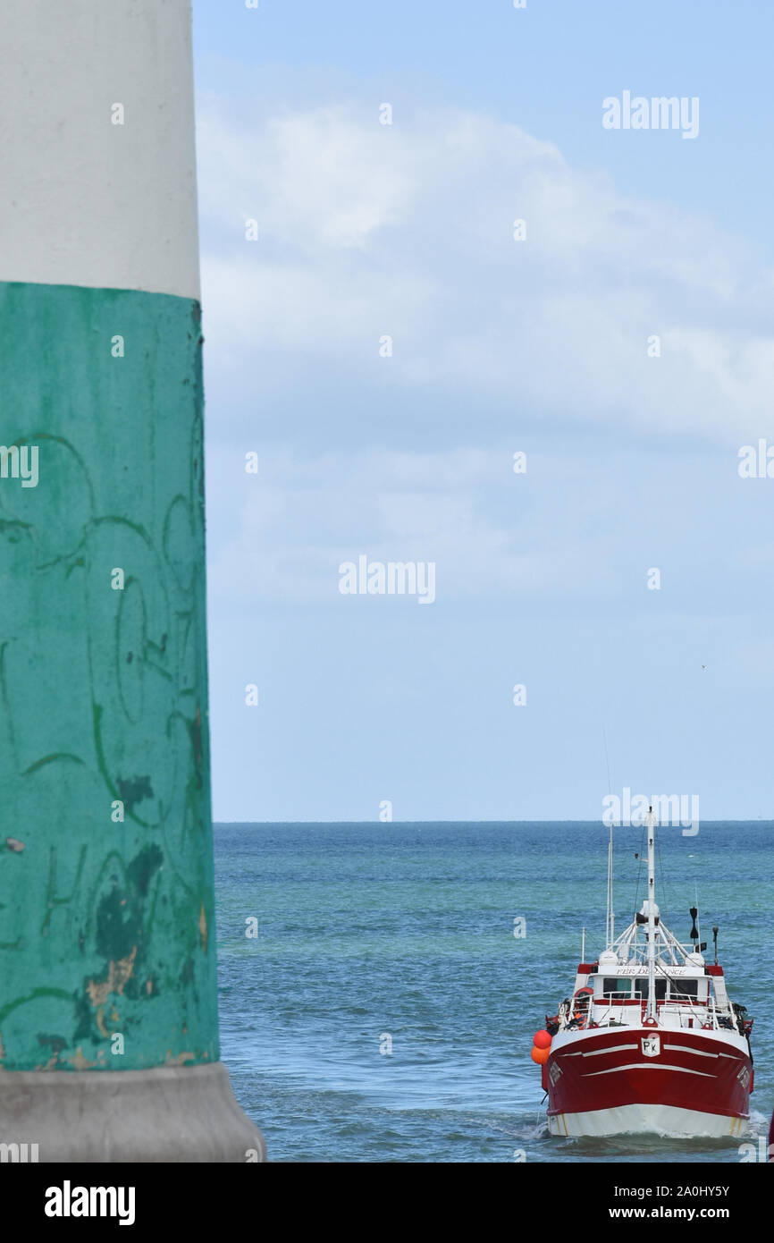 Bateau rentre dans le port du Tréport et phare Foto Stock
