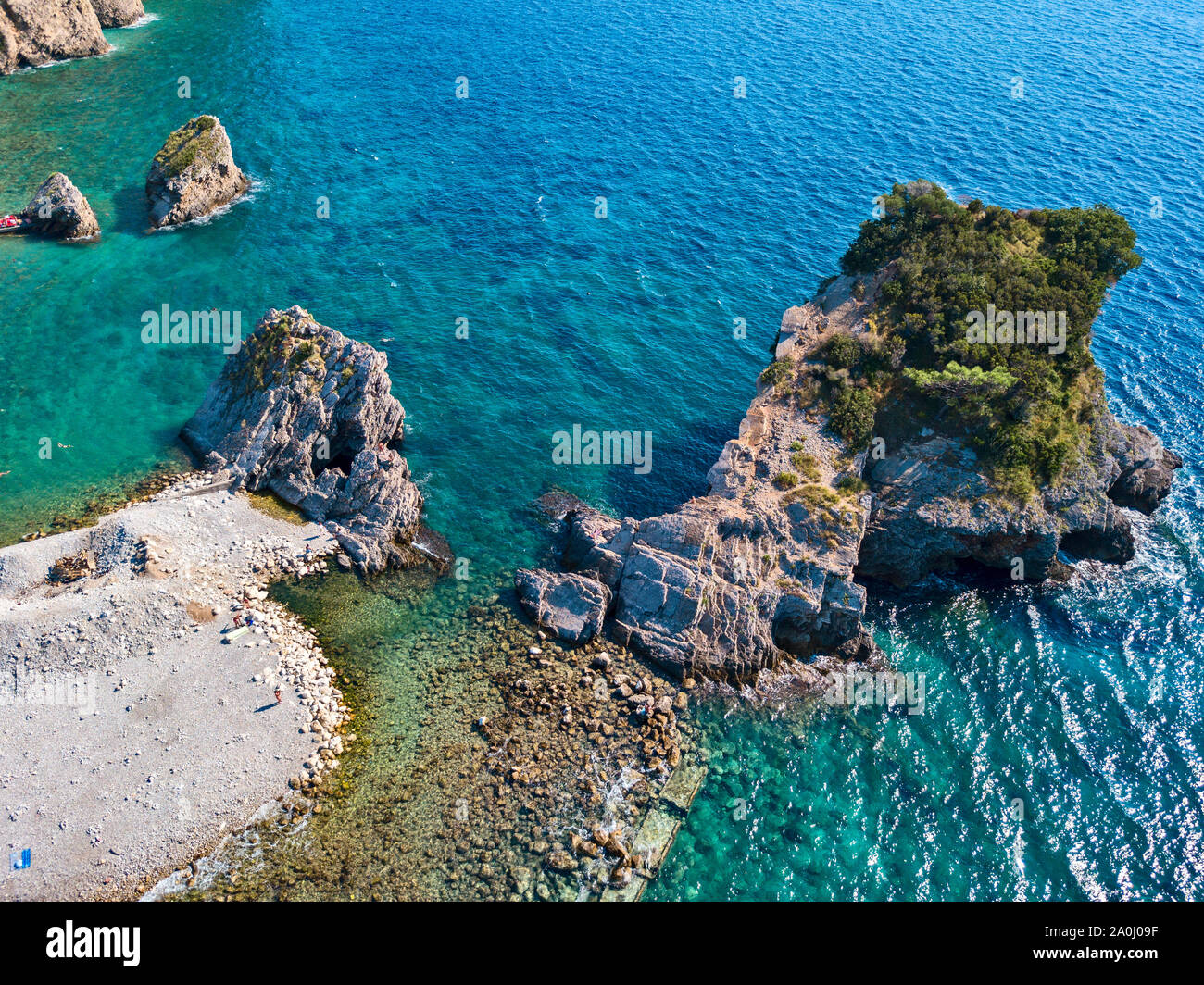 Vista aerea di Sveti Nikola, isola di Budva, Montenegro. Hawaii spiaggia, ombrelloni e bagnanti e acque cristalline. Coste frastagliate Foto Stock