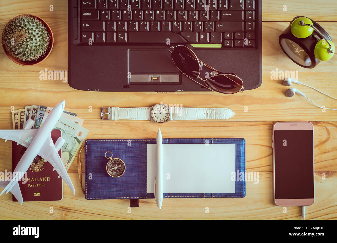 Vista superiore del notebook, penna, occhiali da sole, tazza di caffè, passaporto, denaro, telefono cellulare, auricolari, orologio da polso, cactus, orologio, il mouse del computer e sulla bussola Foto Stock