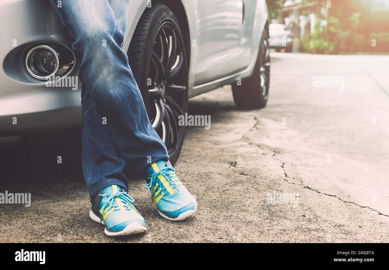 Viaggiatore femmina indossano jeans e scarpe da ginnastica in piedi accanto alla macchina.concetto di viaggio. Foto Stock