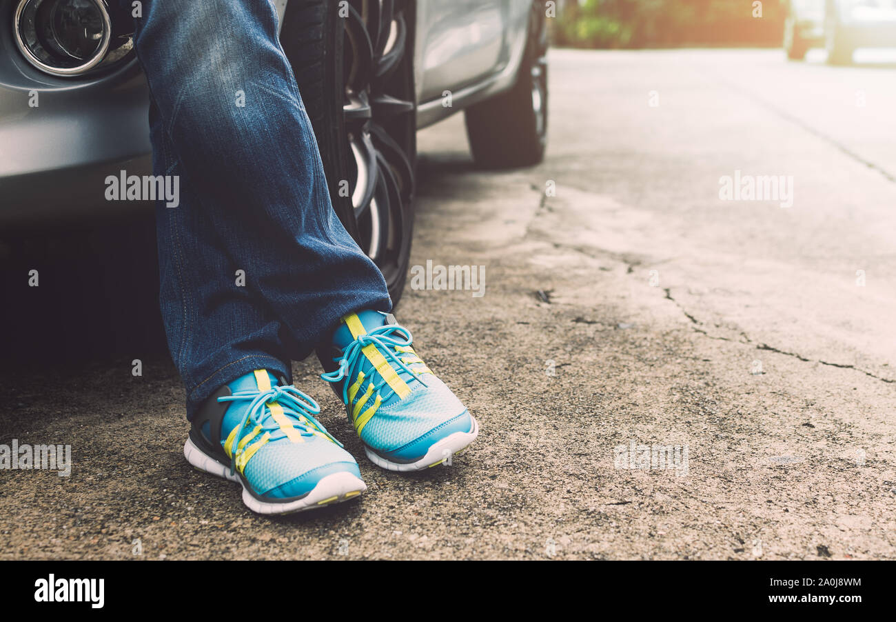 Viaggiatore indossano jeans e scarpe da ginnastica in piedi accanto all'auto. Concetto di viaggio. Foto Stock
