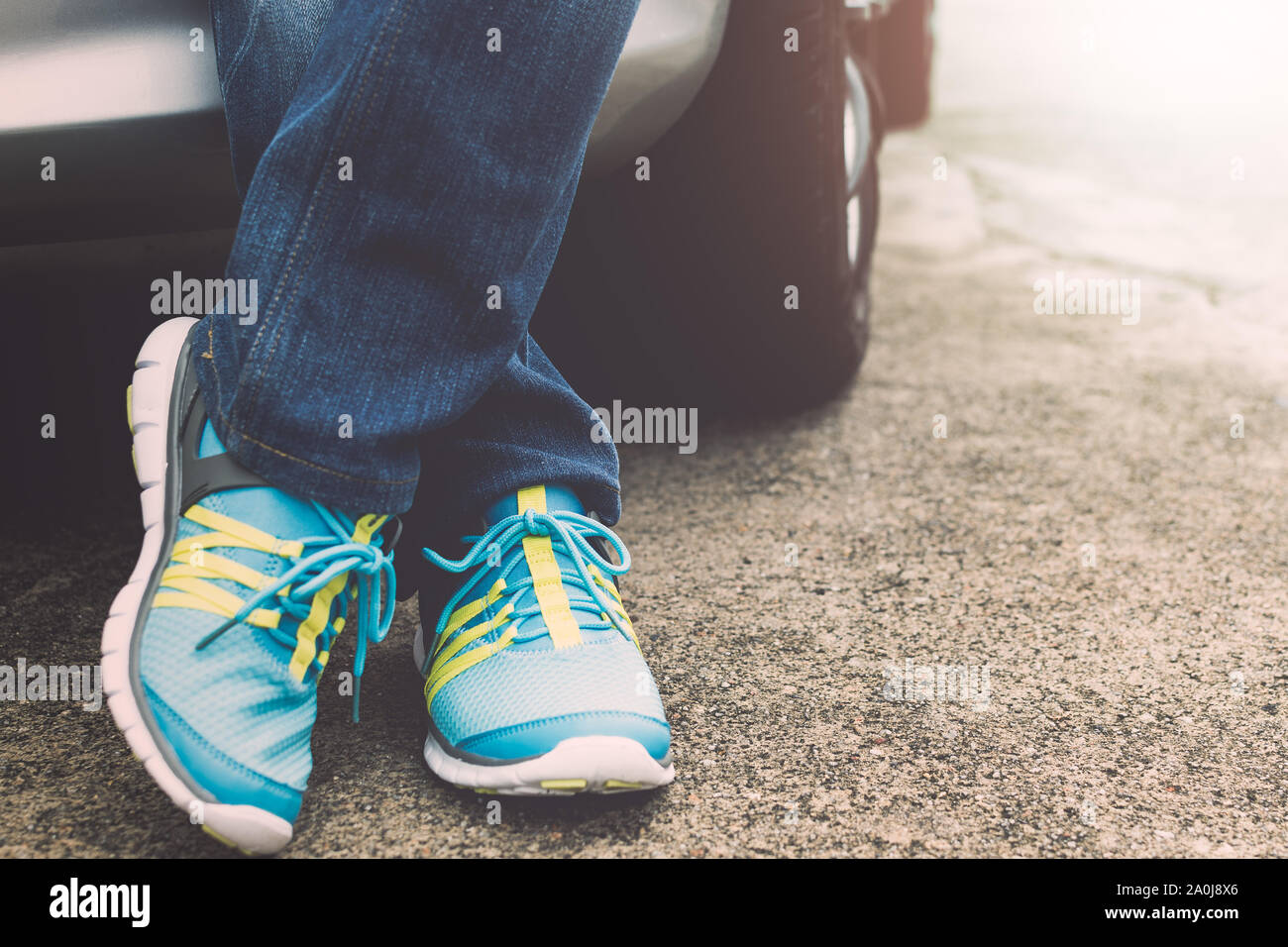Viaggiatore indossano jeans e scarpe da ginnastica in piedi accanto all'auto. Concetto di viaggio. Foto Stock