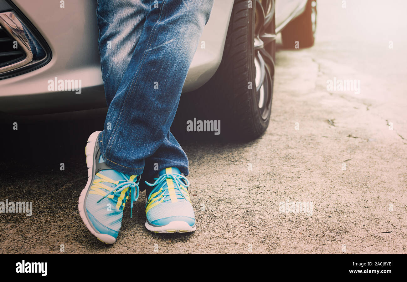 Viaggiatore indossano jeans e scarpe da ginnastica in piedi accanto all'auto. Concetto di viaggio. Foto Stock