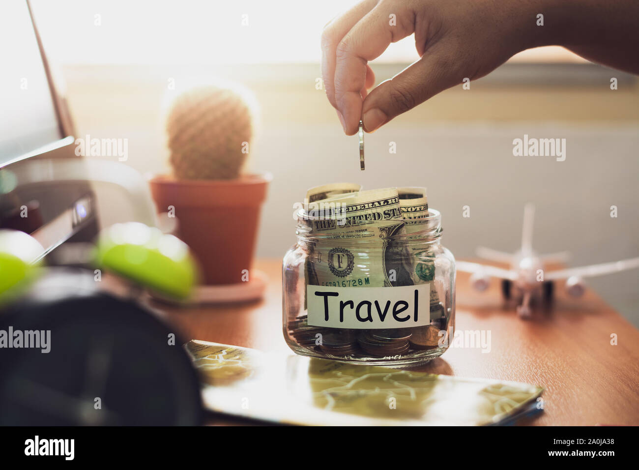 Mano di persone azienda monete mettendo in vetro. Concetto di risparmio di denaro per i viaggi. Piano finanziario. Foto Stock