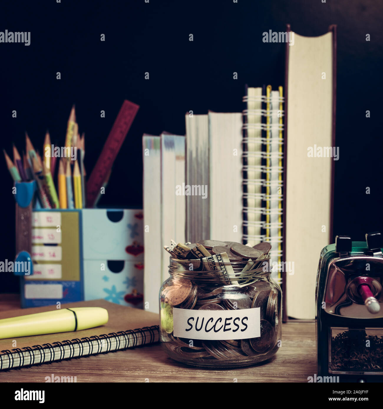 Risparmio di denaro per il successo in un barattolo di vetro con il materiale di studio Foto Stock