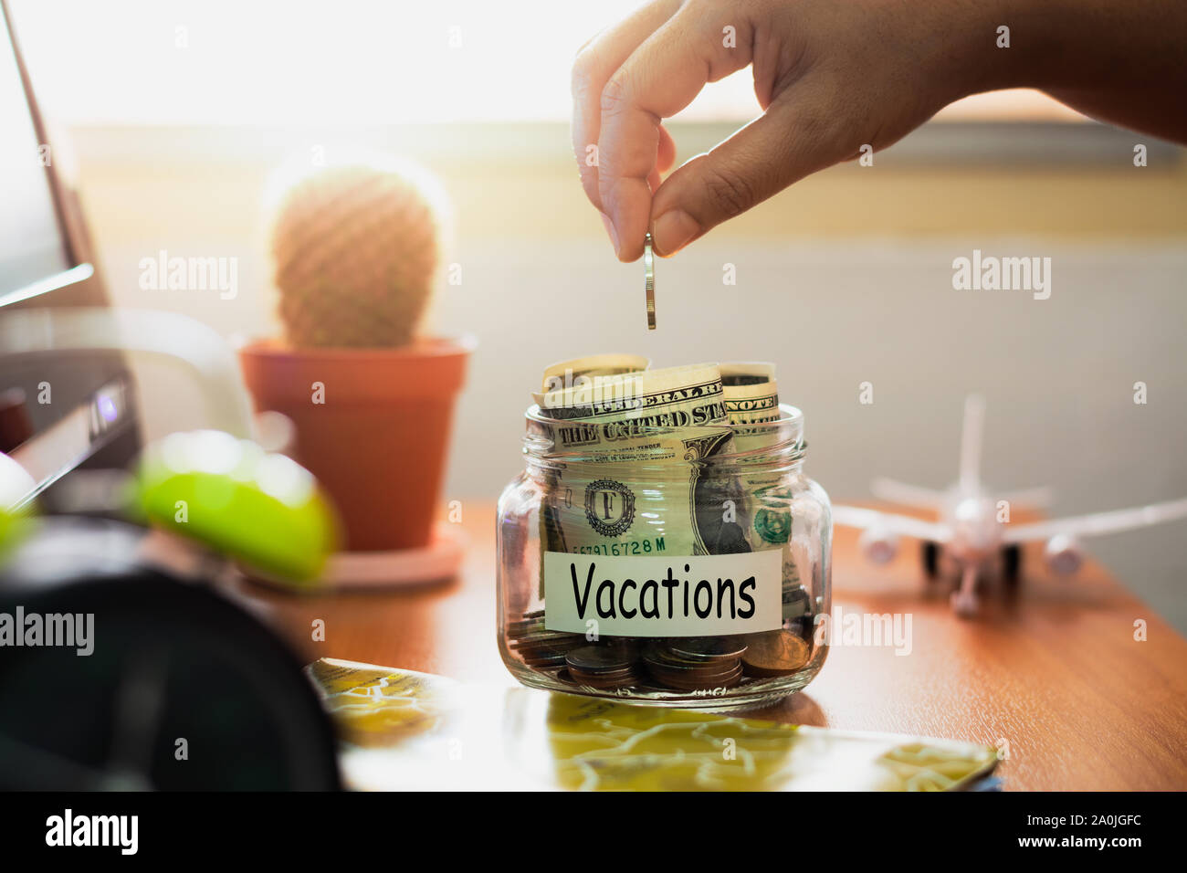 Mano di persone azienda monete mettendo in vetro. Concetto di risparmio di denaro per le vacanze. Piano finanziario. Foto Stock