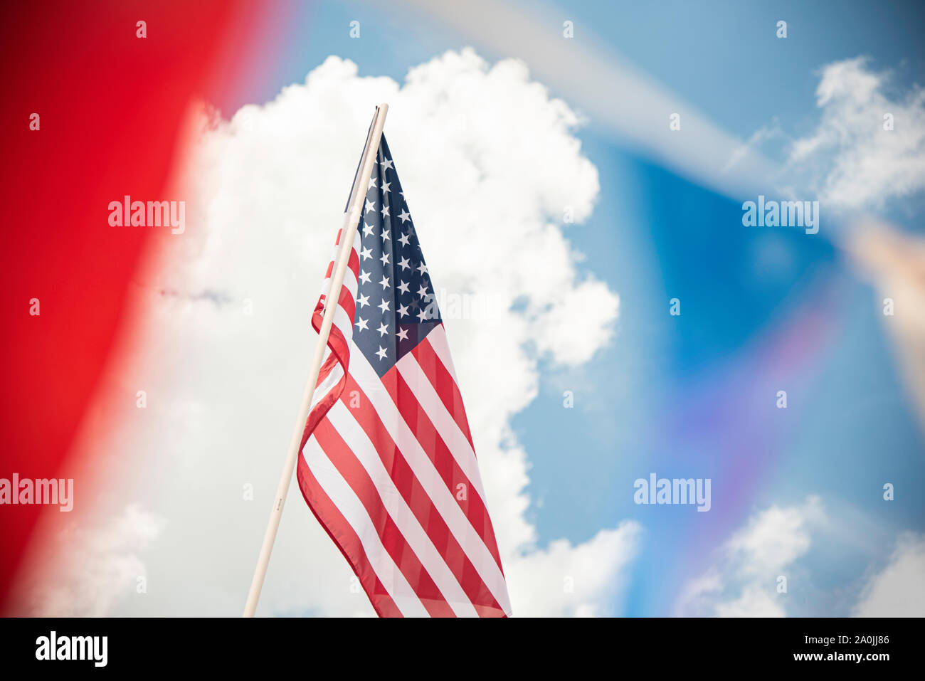 Una bandiera americana impostato sul luminoso cielo blu con nuvole bianche accentuati da nastro colorato banner. Foto Stock