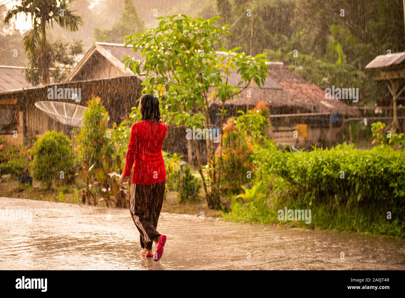 Mentawai tribù donna camminando sotto la pioggia nella città di governo Foto Stock