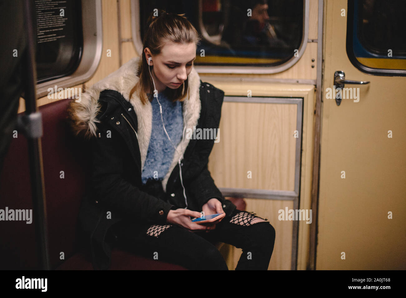 Giovane donna utilizzando smart phone durante il viaggio in treno della metropolitana Foto Stock