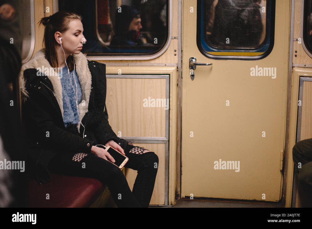 Giovane donna ascoltando musica su smart phone che viaggiano in treno della metropolitana Foto Stock