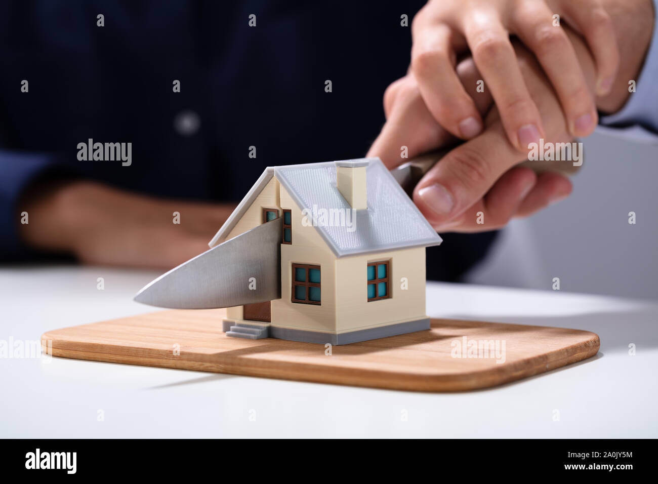 Coppia di taglio a mano la miniatura Modello di casa con il coltello sul tagliere Foto Stock