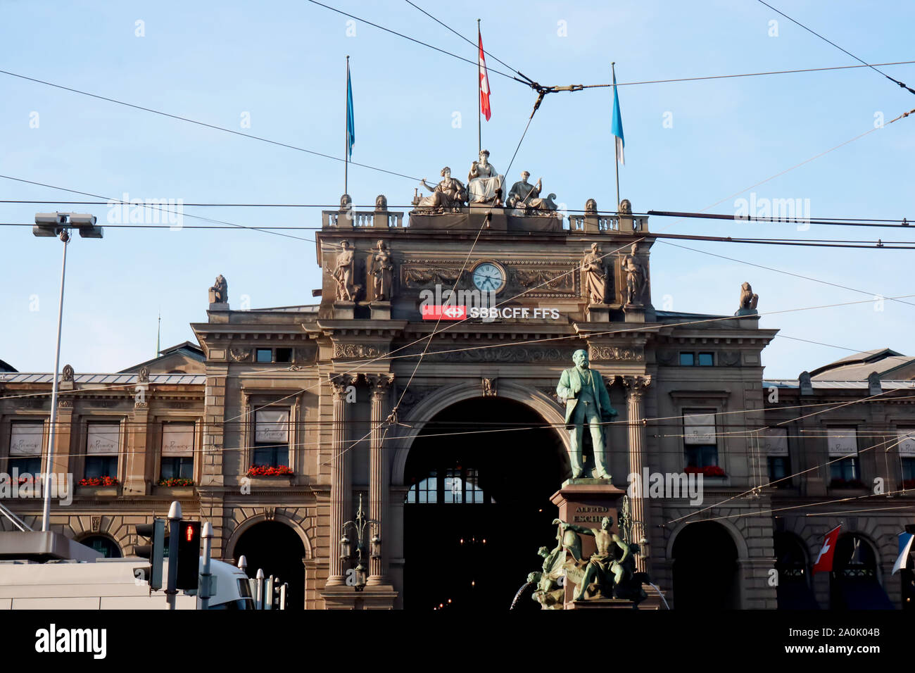 Zurigo, Svizzera,Luglio 19, 2019: Zurigo stazione ferroviaria principale,vecchio edificio con bandiere e fili sopra la strada, con monumento storico nella parte anteriore, Foto Stock