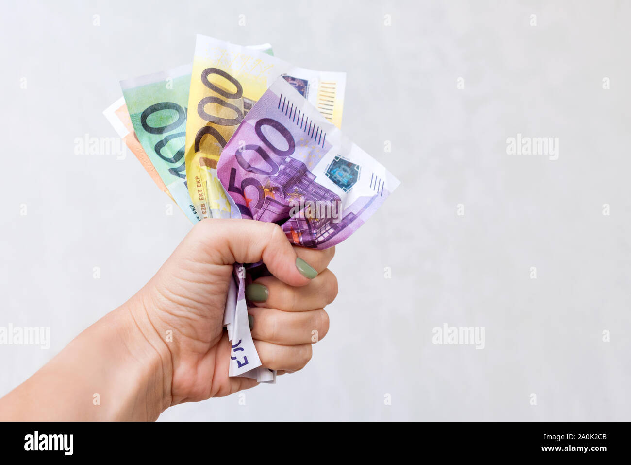 Donna mano azienda accartocciata banconote in euro. Mano trattiene mazzetto di accartocciata in contanti. Messa a fuoco selettiva Foto Stock