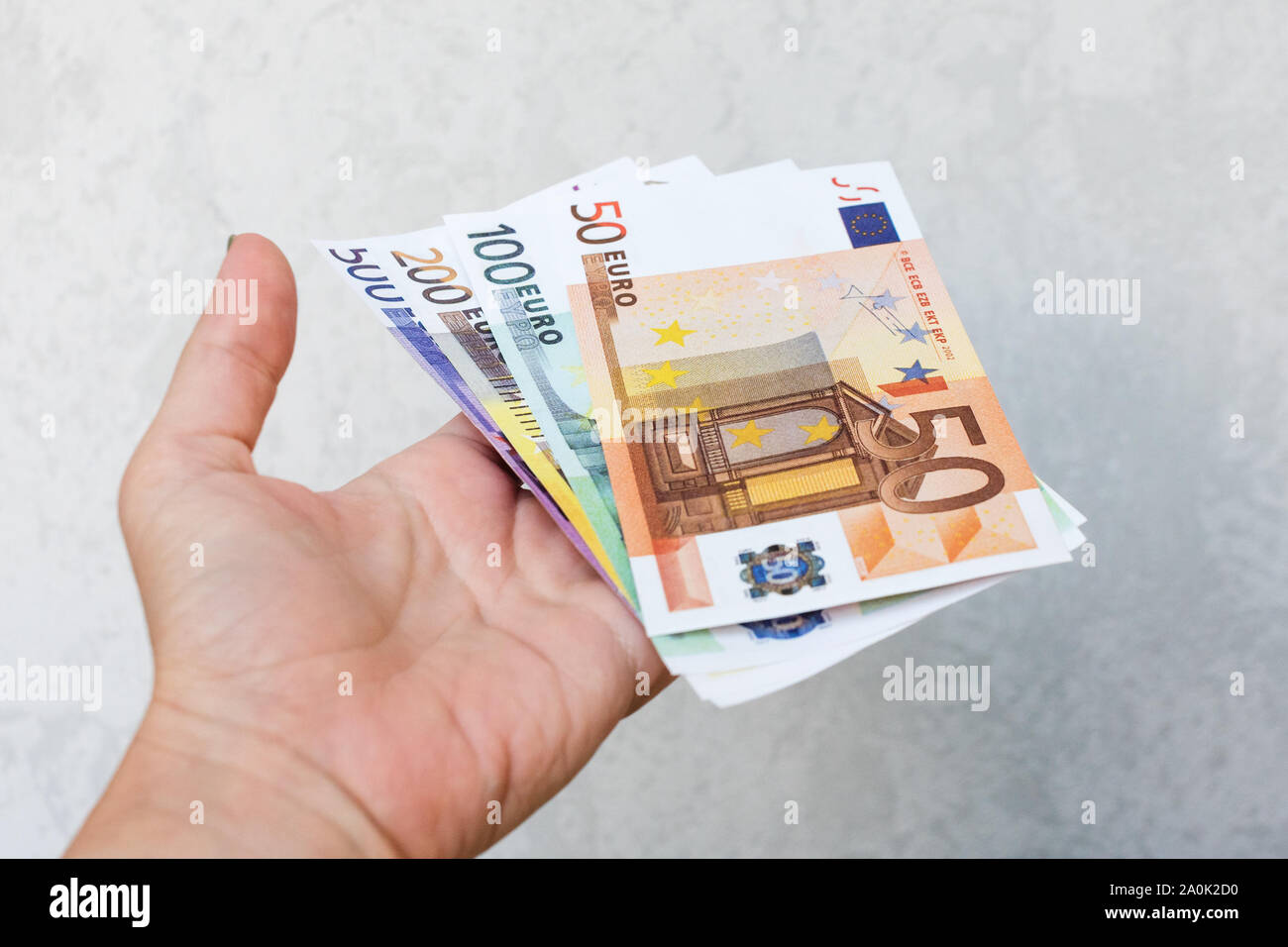 Mano azienda diverse nuove banconote in euro. Mano trattiene mazzetto di contanti Foto Stock