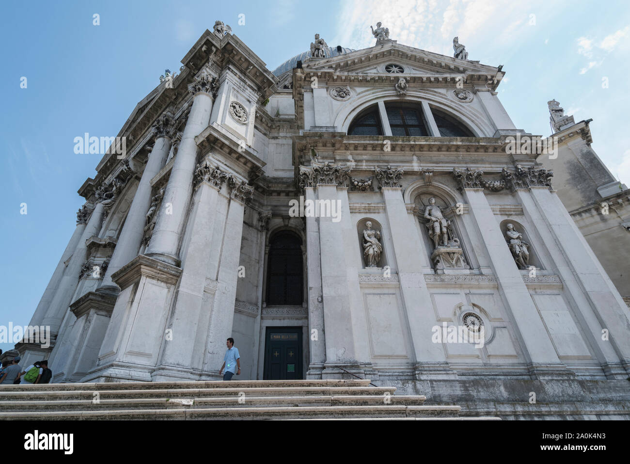 L'uomo cammina al di fuori di un magnifico edificio decorato con sculture e colonne a Venezia, Italia Foto Stock