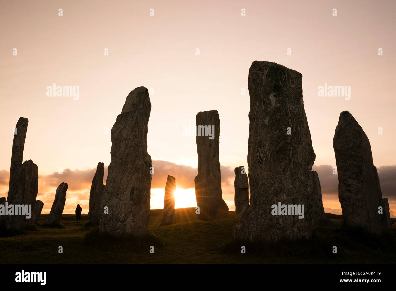 Sun Starburst impostazione Callanish pietre permanente stagliano contro un cielo color pastello dell'isola di Lewis, Ebridi Esterne, Scotland, Regno Unito, Europa Foto Stock