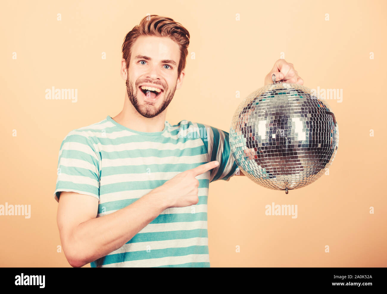 Come circa la parte. Uomo bello tenere palla da discoteca. Danze da discoteca night club. Musica retrò. Ragazzo che vi invitano a parte. Migliaia di minuscoli specchi che riflettono la creazione delle luci di atmosfera da discoteca. Allegro dj uomo. Foto Stock