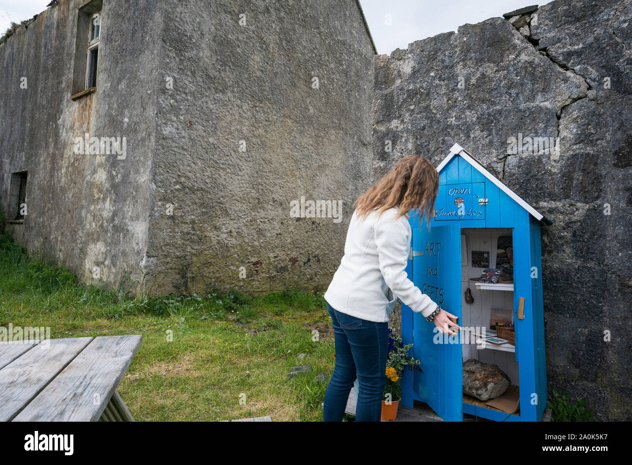 Turista femminile si apre una casella di onestà si trova vicino Rodel sulla punta meridionale di Harris, isola di Lewis, Ebridi Esterne, Scozia, Regno Unito, Europa. Casella di onestà Foto Stock