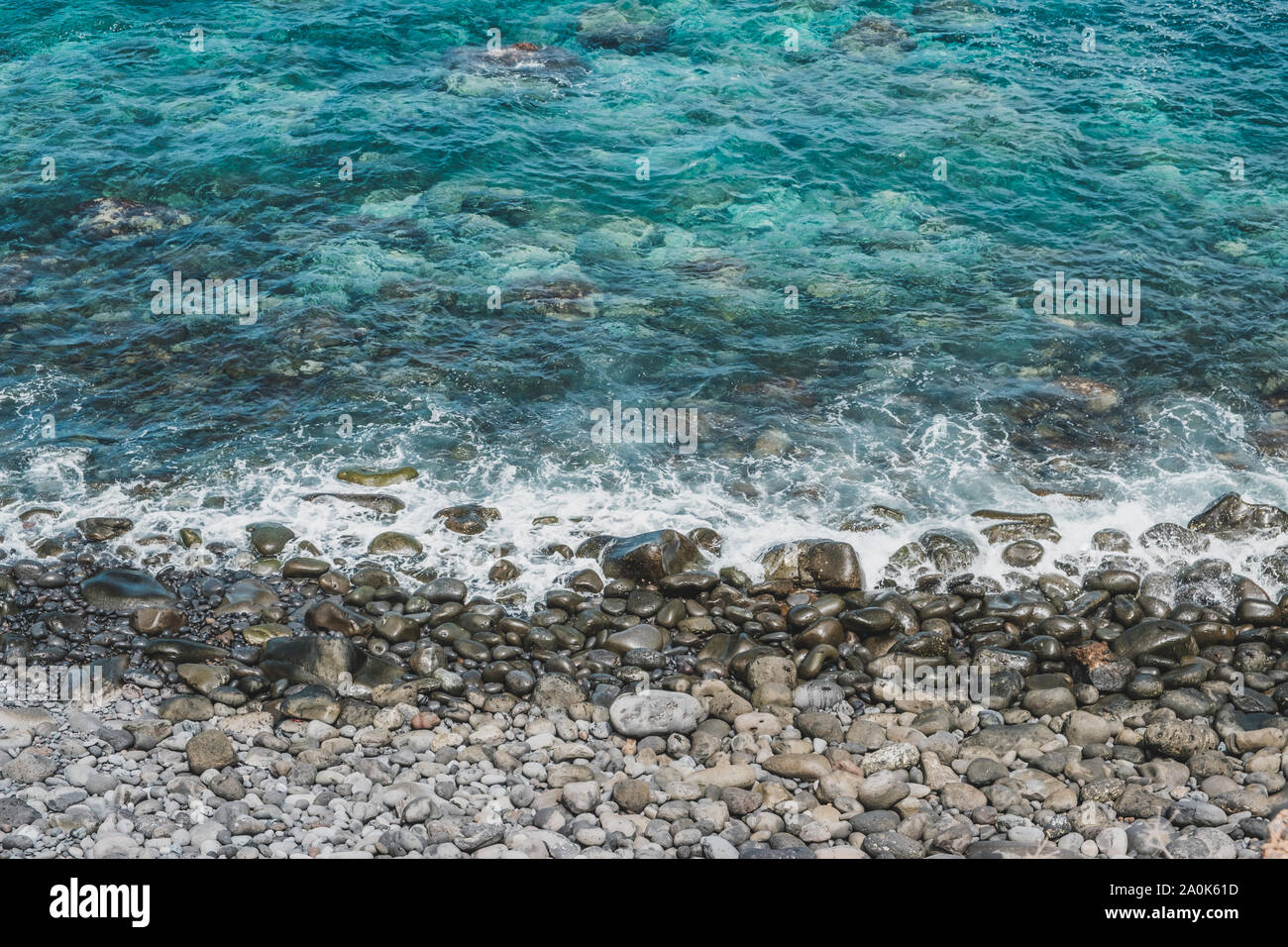 Le onde del mare sulla spiaggia di pietra con ciottoli neri - Foto Stock