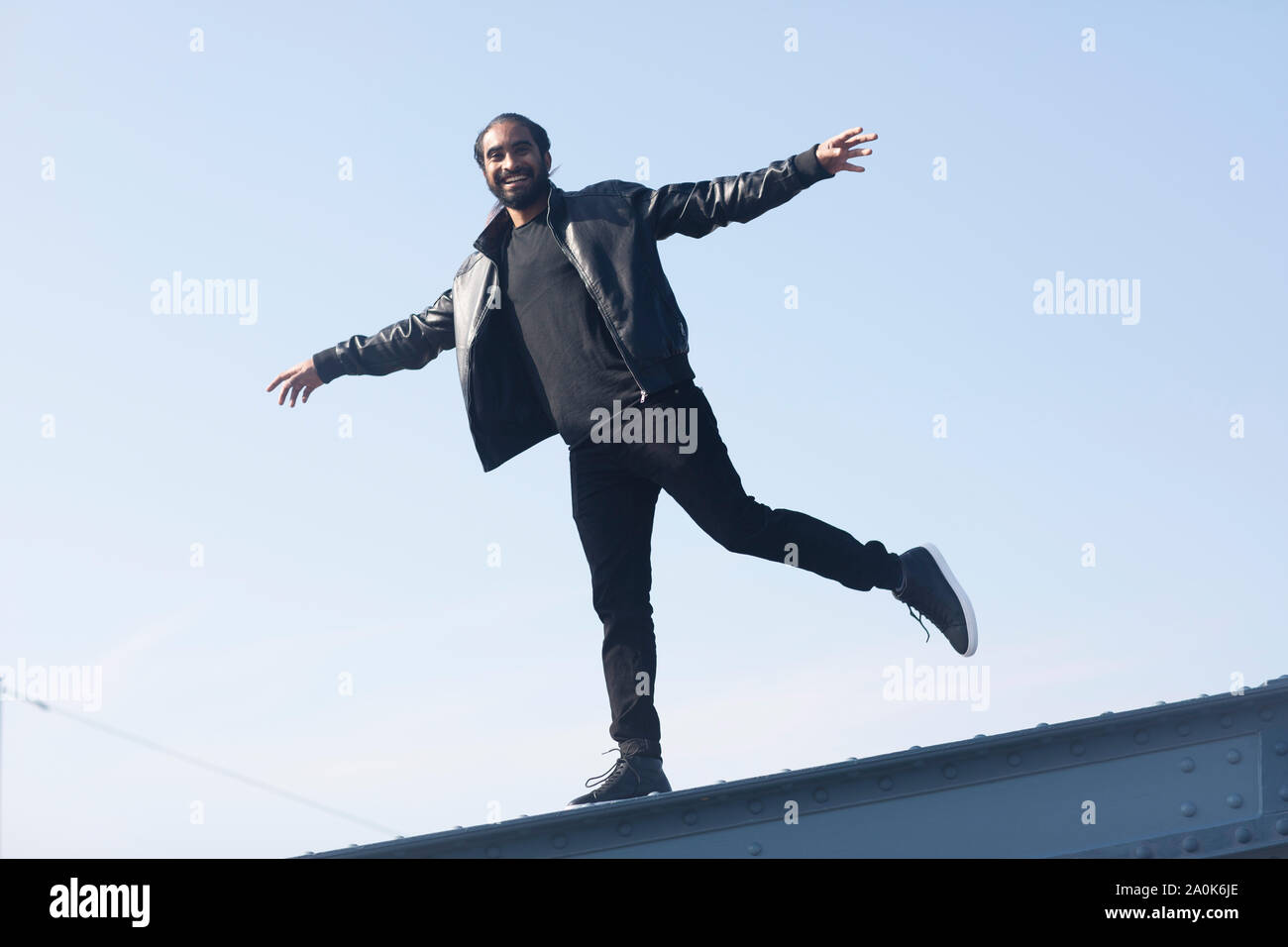 Giovane con treccia e barba in equilibrio su un ponte Foto Stock