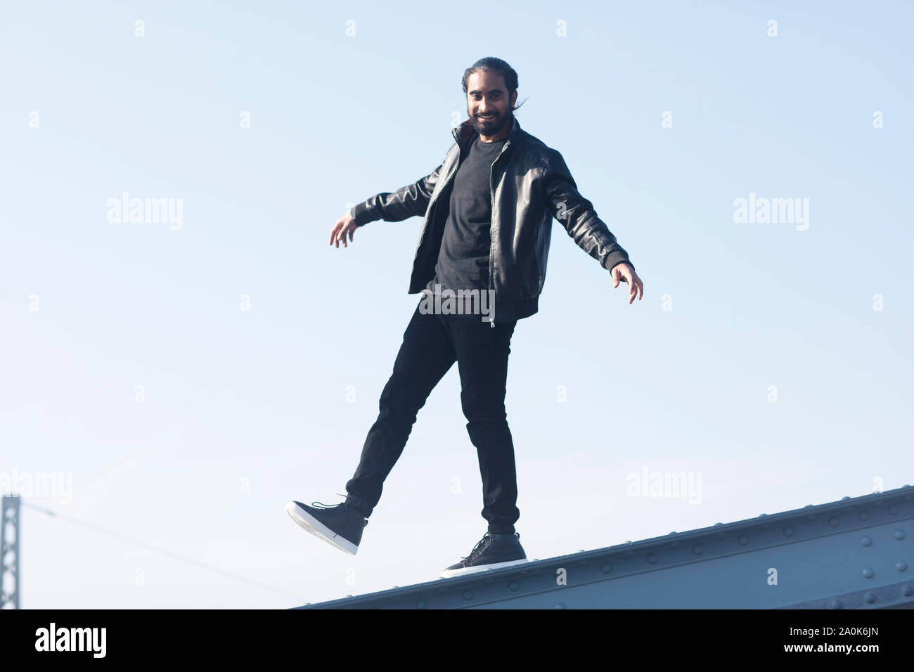 Giovane con treccia e barba in equilibrio su un ponte Foto Stock