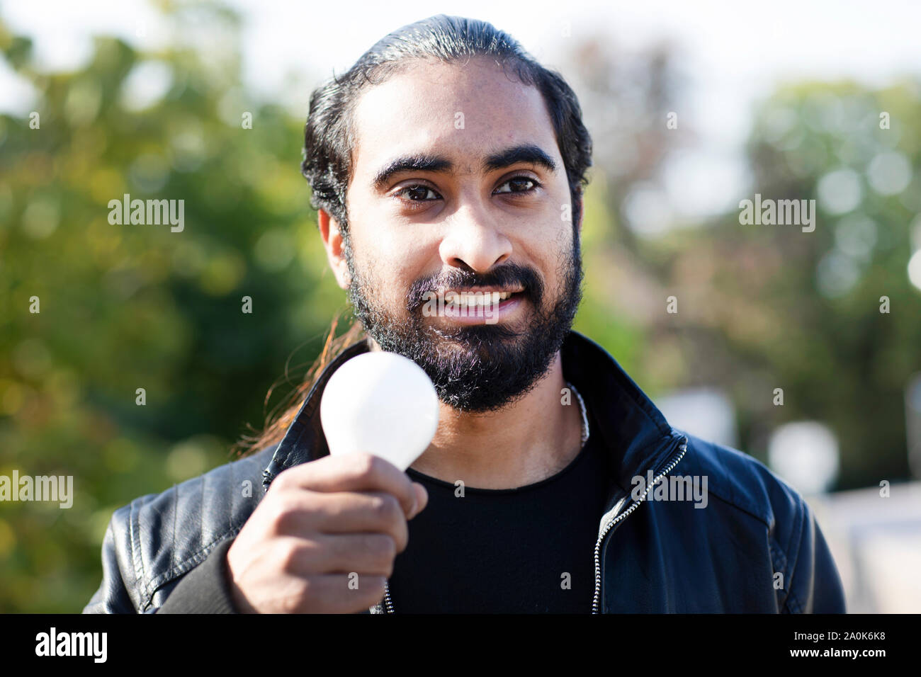 Giovane con treccia e barba tenendo con la lampadina in mano Foto Stock