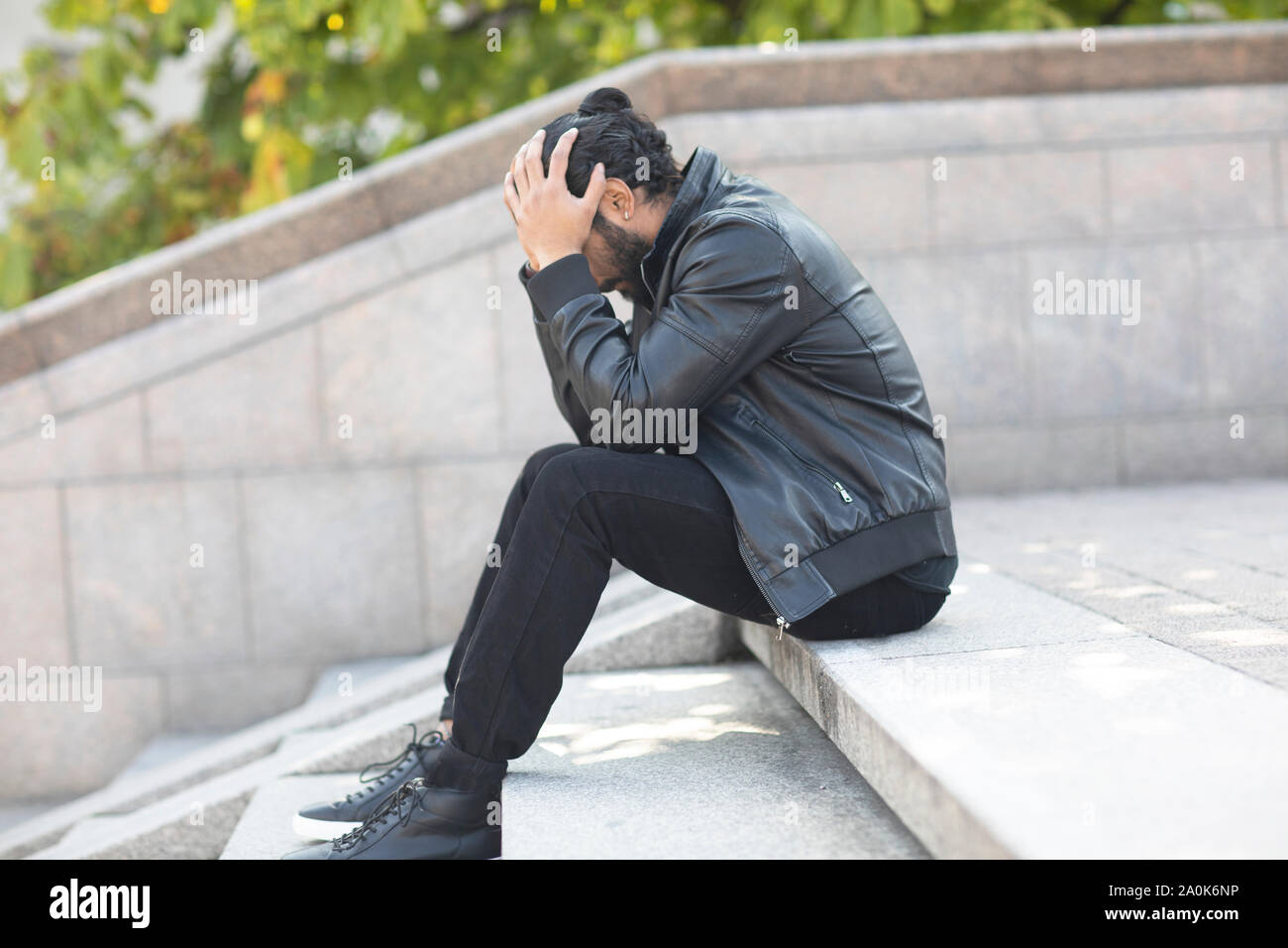 Giovane uomo seduto su una scala frustated mani prima di faccia Foto Stock