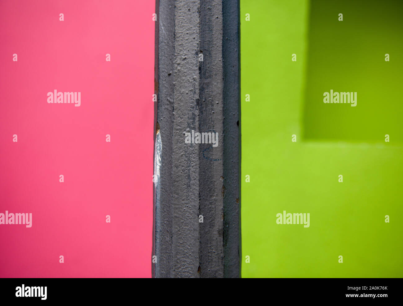 Coloratissima casa coloniale parete contrasta con antichi nero palo in acciaio Foto Stock