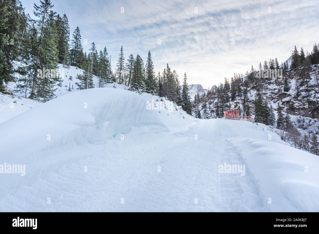 Paesaggio invernale con la neve di alberi di pino e i grandi cumuli di neve sul lato di una strada di montagna. Il paesaggio alpino nelle vicinanze del villaggio austriaco Foto Stock
