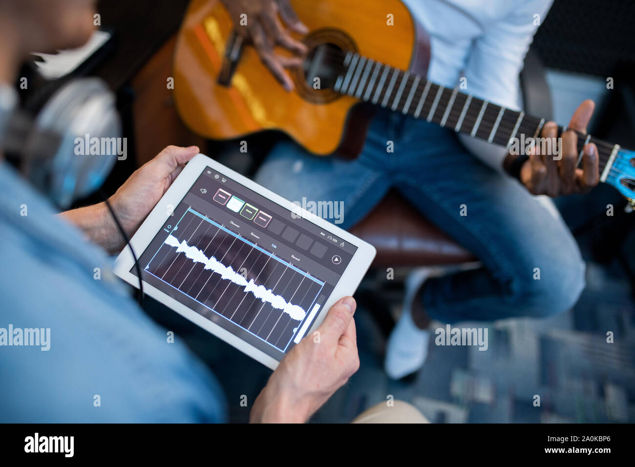 Touchpad con forme d'onda sonora sul suo visualizzatore detenute da giovane musicista contemporaneo Foto Stock
