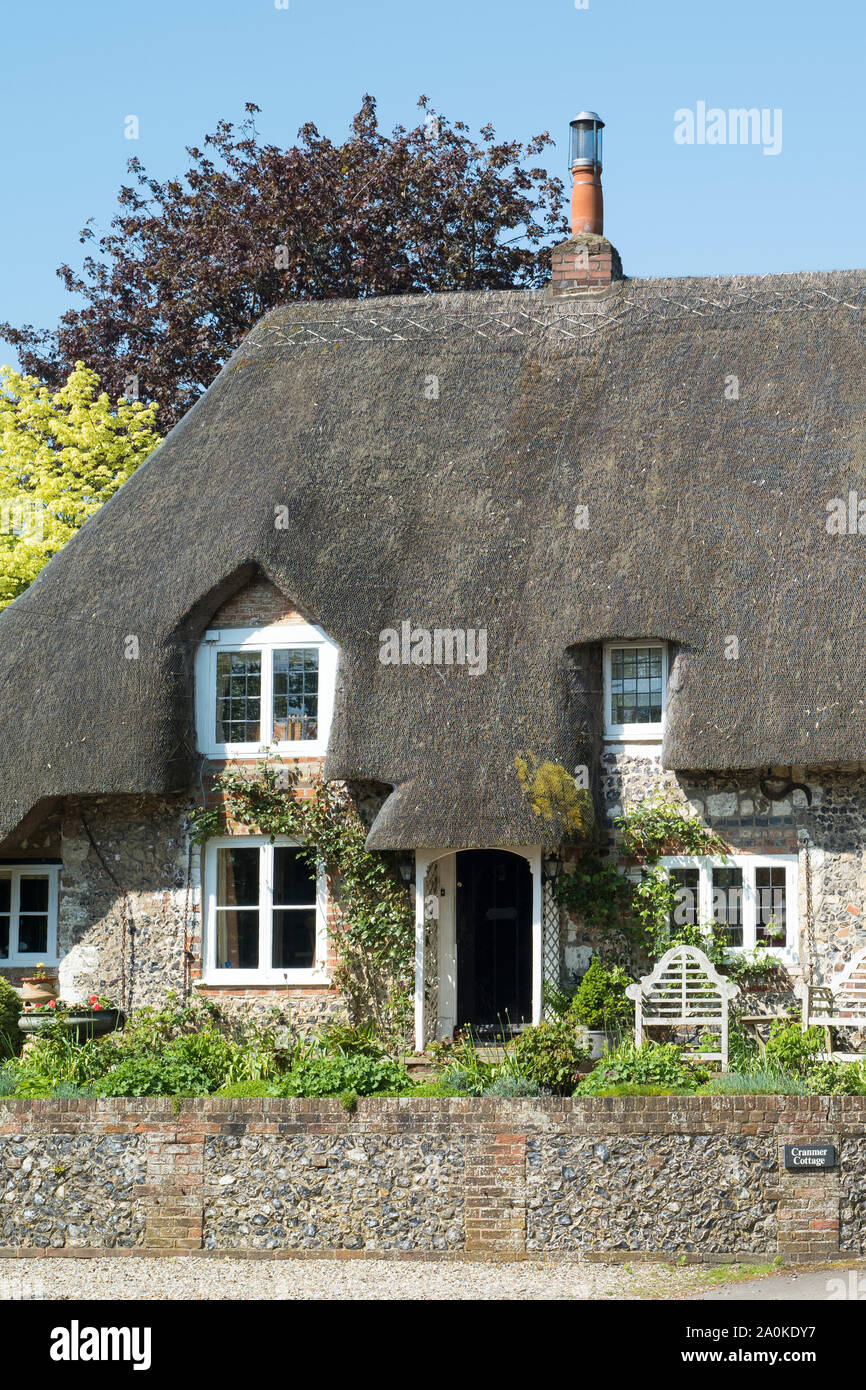 Inglese tipica pietra costruito cottage con tetto in paglia in mattoni e pietra focaia costruzione tetto, ricoprendo di paglia, camini in Ramsbury, Wiltshire, Regno Unito Foto Stock