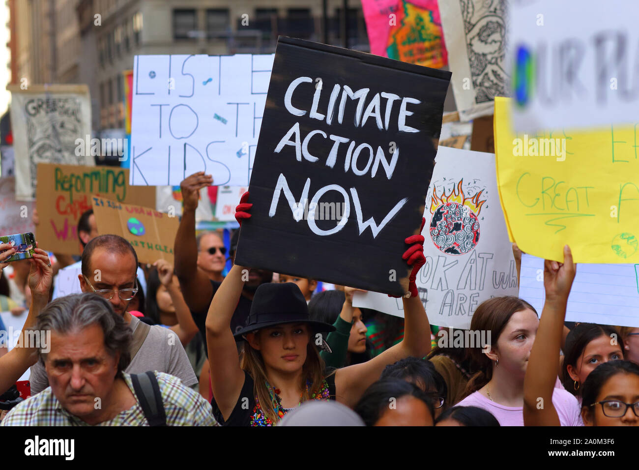 New York, New York. 20 settembre 2019. Una donna ha un segno 'azione del clima ora' al colpo di clima guidato dai giovani di NYC. Decine di migliaia di persone, studenti hanno partecipato alla marcia e radunano a Broadway fino a Battery Park con Greta Thunberg come partecipante e ospite. Foto Stock