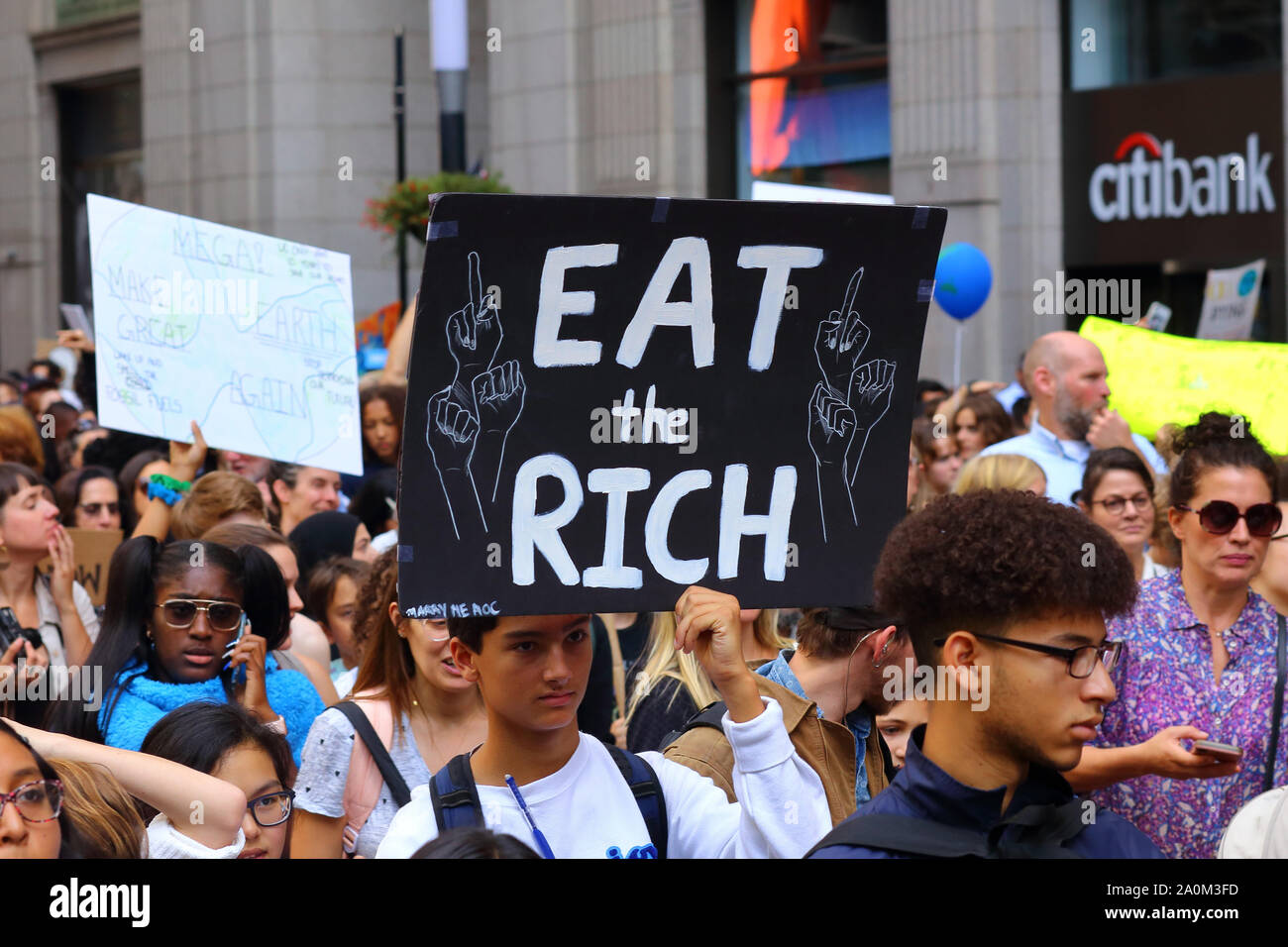 New York, New York. 20 settembre 2019. Un giovane ha un segno 'mangia i ricchi' al colpo di clima guidato dai giovani di New York. Decine di migliaia di persone, studenti hanno partecipato alla marcia e radunano a Broadway fino a Battery Park con Greta Thunberg come partecipante e ospite. Foto Stock