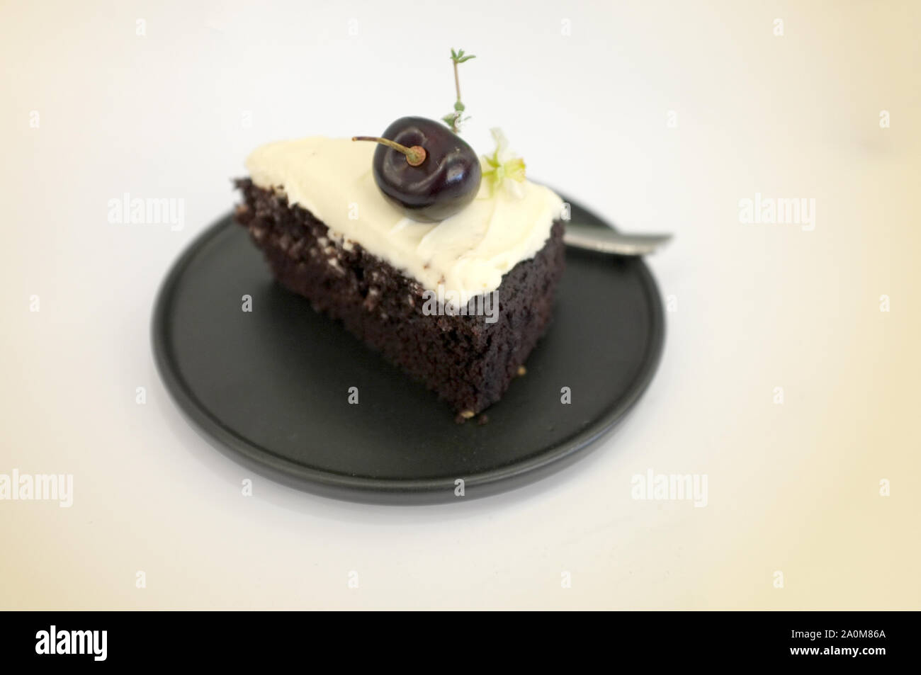 Birra nera torta. Un pezzo di torta nera con sapore di birra e rabboccato con crema di formaggio e di ciliegio Foto Stock
