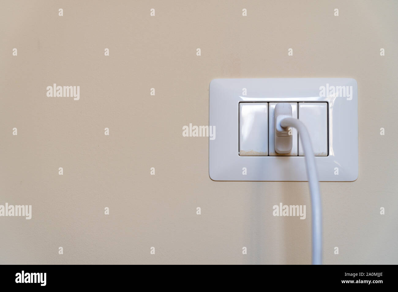 Il cavo bianco collegato in un bianco italiano di uscita elettrico montato sulla parete Foto Stock