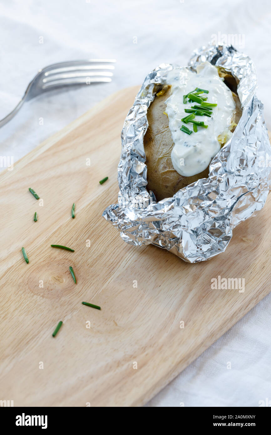 Cotta nel forno Potatoe con crema a base di erbe formaggio sulla tavola di legno Foto Stock