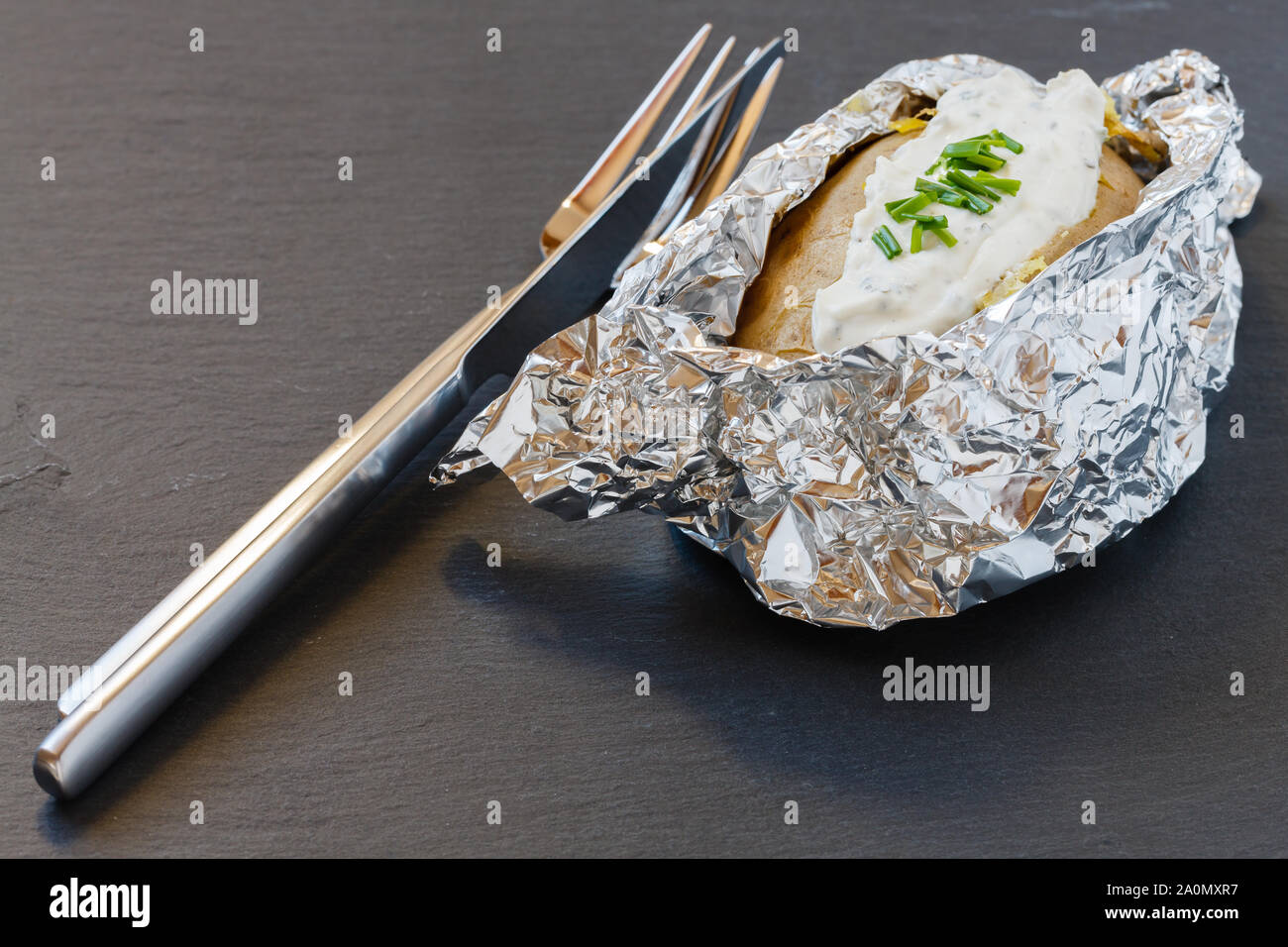 Forno di patate al forno al cartoccio con crema a base di erbe formaggio sulla scheda di ardesia Foto Stock