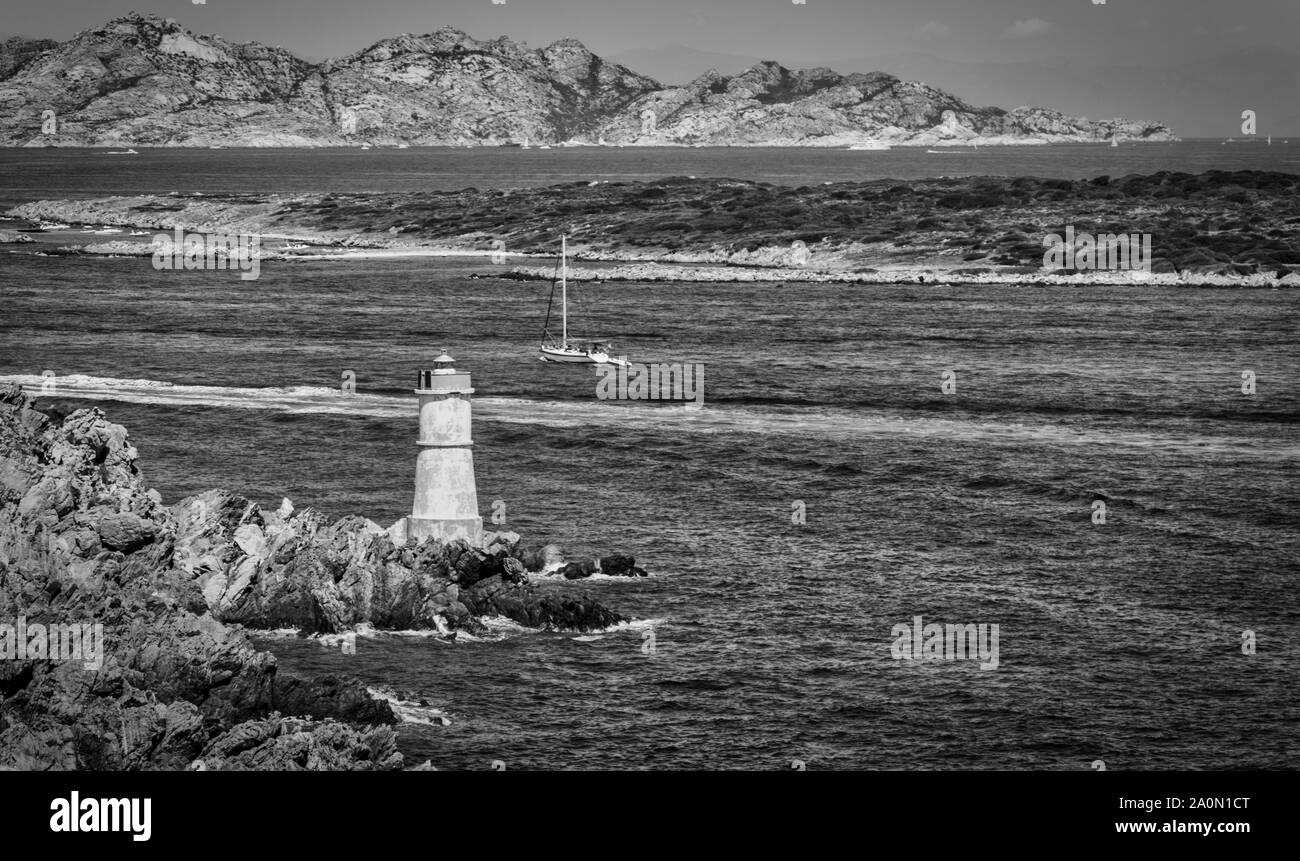 Costa della Sardegna con un faro e una barca a vela in bianco e nero Foto Stock