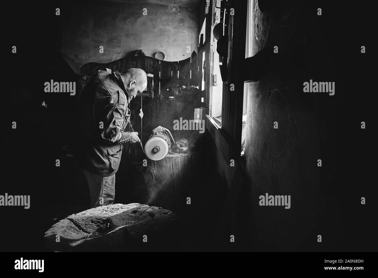 Il lavoratore di grind un metallo dettaglio sulla rettificatrice con una mola abrasiva Foto Stock