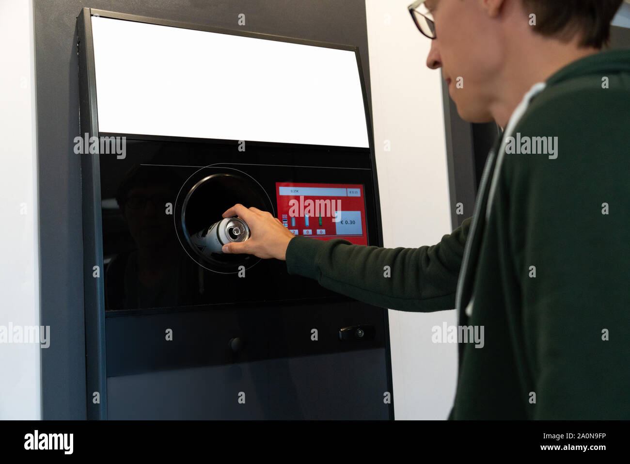 L'uomo utilizza un self service per ricevere bottiglie di plastica usate e lattine in un negozio Foto Stock