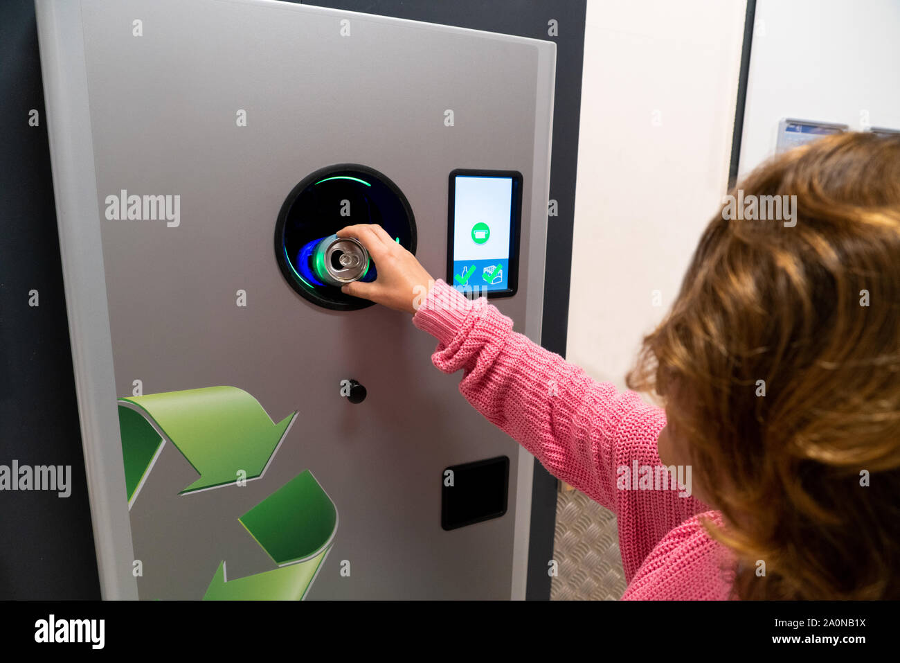 Una donna utilizza un self service per ricevere bottiglie di plastica usate e lattine in un negozio Foto Stock